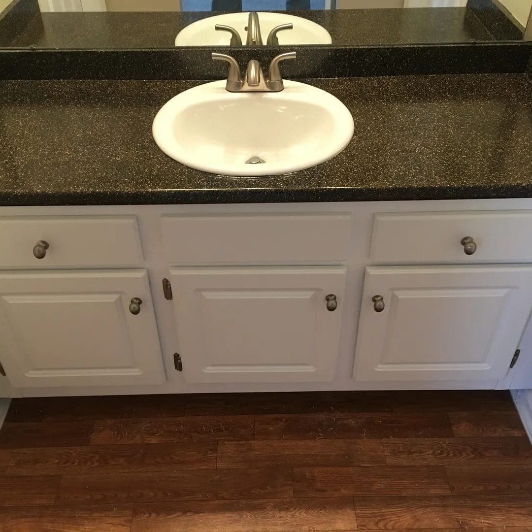 89928a8e48990e95006d8f8249aa0232 White bathroom vanity with black countertop.